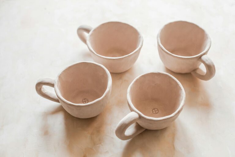 Handmade ceramic cups on light surface